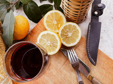 Argentinian asado scene with grilled meat, fresh lemons, rustic cutlery and a glass of red wine on a wooden board, evoking traditional outdoor gourmet dining and celebration