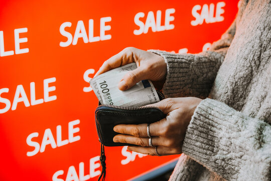 Person taking euro banknotes from wallet during sale shopping.