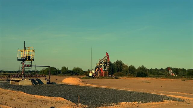 Oil extraction on sunrise. Crude pump jack working on oil field on sunset. Industrial landscape mood. Pumpjack in oil well of oil field on sunrise in Industrial crude area. 