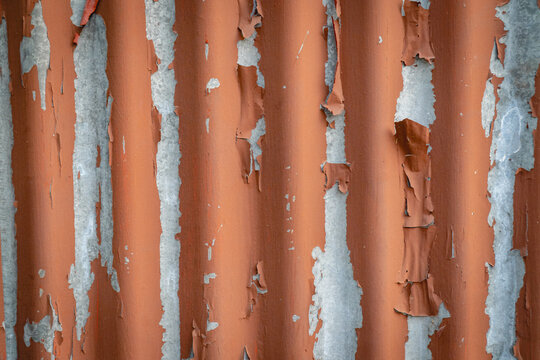 Weathered orange metal bars with peeling paint and exposed gray surface, creating a distressed industrial texture.