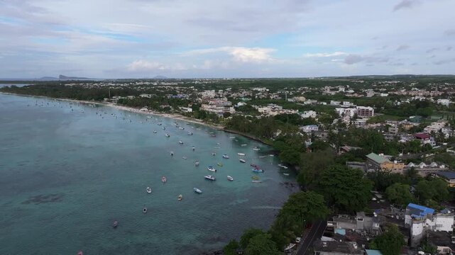 Aerial view of Trou aux Biches Beach with turquoise water, small boats, and coastal buildings in Pamplemousses District, Mauritius.
