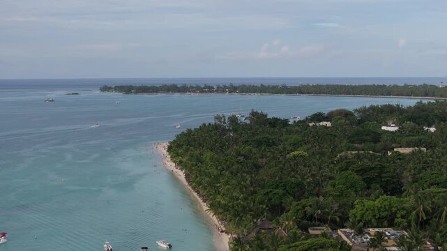Aerial view of Trou aux Biches Beach with turquoise water, lush palm trees, and boats along the coastline in Pamplemousses District, Mauritius.