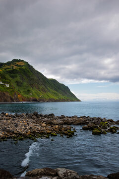 Povoa&ccedil;&atilde;o volcanic coast on S&atilde;o Miguel, Azores: lush green cliffs and rocky shoreline meeting the Atlantic under moody skies, dramatic, rugged island seascape