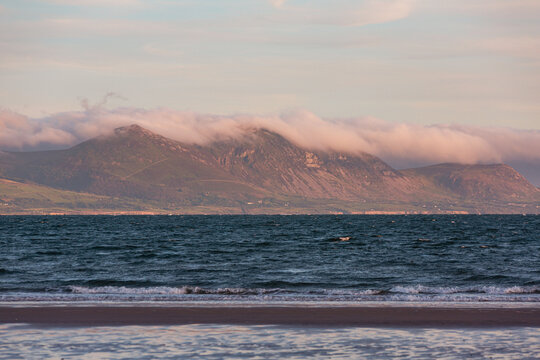 Evening light on the welsh villages and mountains of the Llŷn Peninsula with dramatic cloud rolling over the peaks, viewed from Anglesey