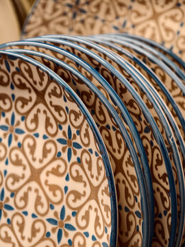 Luxurious patterned ceramic plates with blue rim on shelves in store, close up of table plates for household and kitchen