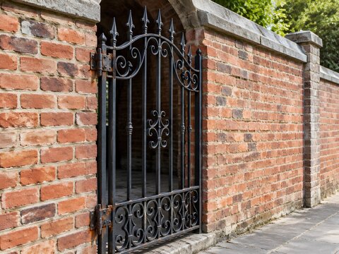 A single wrought iron gate of scrollwork and spearhead finials