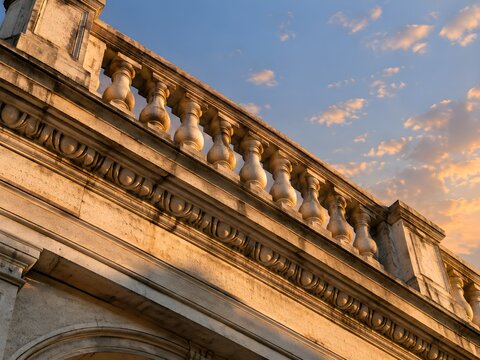 A stone balustrade and carved cornice running along the parapet of a civic front chunky turned balusters under a plainl