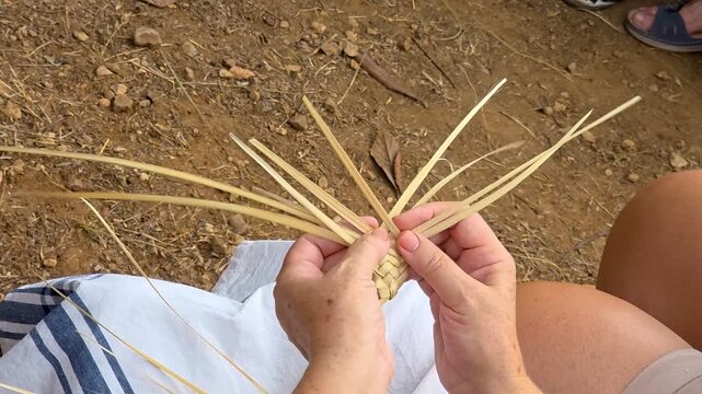 Top view of artisan hands weaving dried esparto grass braid, traditional Spanish craft and handmade manufacturing process.
