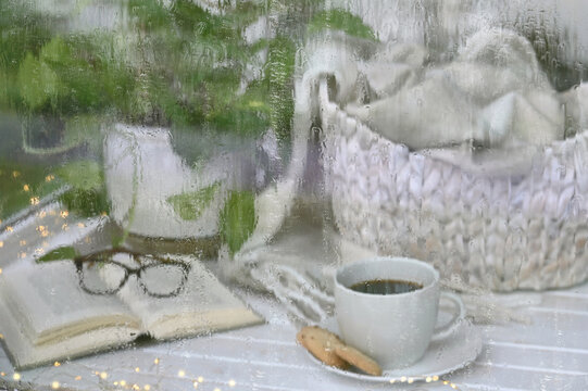 Rainy Day Window - Hot tea coffee with book and blanket behind rain covered glass