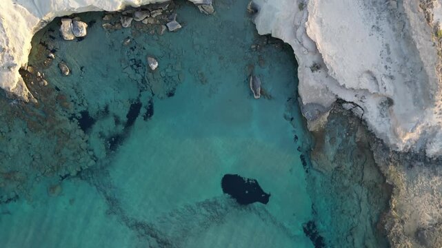 Aerial Top Down View of White Cliffs and Turquoise Cove in Greece