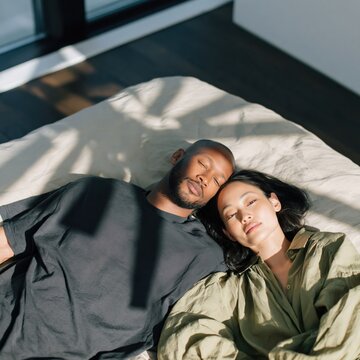 Content couple reclining on a bed with gentle sunlight casting shadows for peaceful bedroom background and contemporary home lifestyle banner