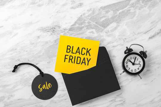 Black friday sale background, yellow card and envelope with alarm clock on marble table, copy space