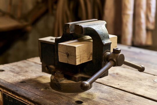 Cast iron workbench vise gripping a block of wood, holding and clamping concept