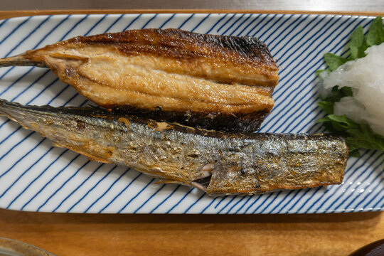Grilled Pacific saury served on a traditional Japanese rectangular plate with grated daikon radish