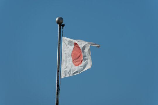 National flag of Japan Hinomaru waving in the wind under clear blue sky with copy space