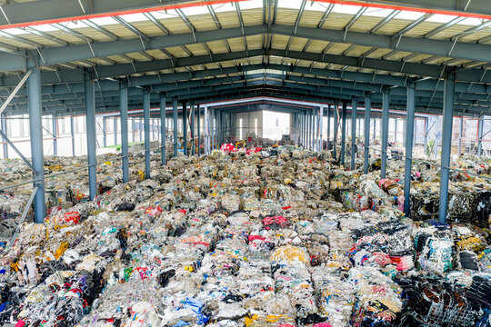 Piles of waste textile materials stored in a large recycling warehouse
