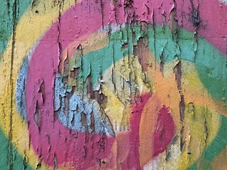 Detailed close-up distressed pink, orange, teal peeling spiral graffiti street art © LilliM