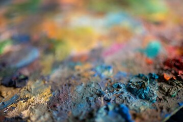 Fototapeta premium Closeup painter palette surface with dried mixed oil paints and textured brushstrokes in warm