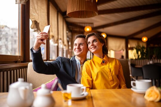 Couple taking a selfie with a smartphone at a cafe table