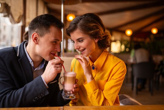 Happy young man feeding a dessert to a woman with a spoon