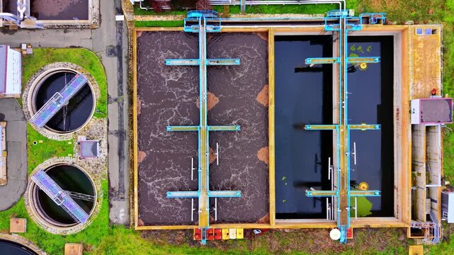 Rectangular and circular tanks at a large wastewater treatment site. Aeration channels, round clarifiers and a network of blue walkways span the complex.