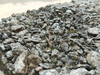 Close-up of a rough concrete surface with exposed grey pebbles and small stones, featuring a shallow depth of field © Ricko Destu