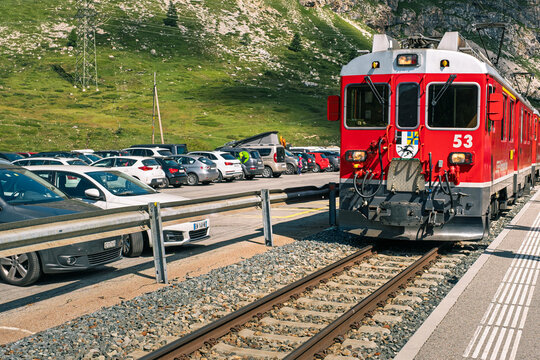 Diavolezza Switzerland - August 14 2021: Red Rhaetian Railway train arriving at Bernina Diavolezza station in Graubunden surrounded by scenic alpine landscape during a sunny summer day