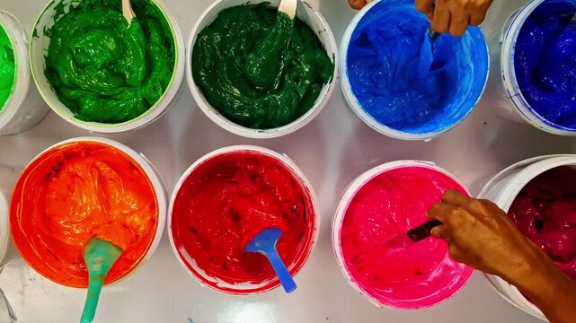 Top view, colorful fabric printing inks in white buckets.
Stirring the ink for multicolored tee shirt printing .
colorful of ink for print tee shirt in tee shirt factory.
colorful ink background.