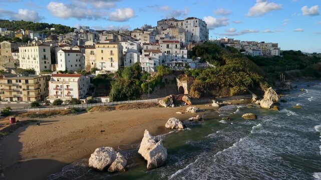 Rodi Garganico Italy white town and Scoglio del Leone rocks aerial drone view from sea at golden sunrise. Empty beach in Gargano Puglia 4K Italian summer destination