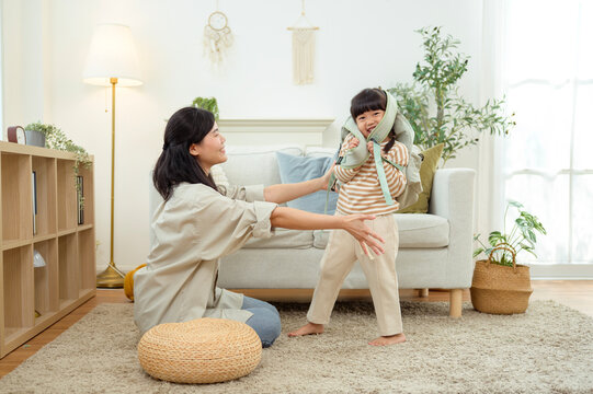 Asian mother helping young daughter prepare a backpack for school at home