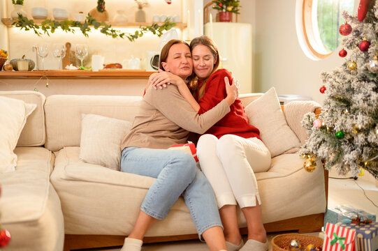 Mom and Daughter Share a Hug During a Family Moment in Front of a Christmas Tree