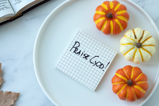 Praise God, handwritten text note with holy bible and pumpkin decoration. Christian thanksgiving, blessing, and gratitude concept.