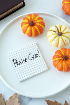 Praise God, handwritten quote with holy bible and pumpkin decoration. Christian thanksgiving, blessing, and gratitude concept.