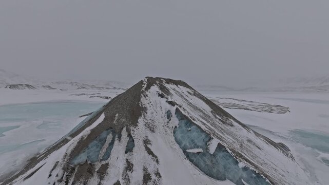 Aerial view of the pyramid-shaped mountain peak covered in snow and blue glacial ice in the Arctic landscape of Pyramiden, Svalbard, Svalbard and Jan Mayen.