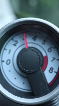 Vertical screen detailed car tachometer with the needle climbing rapidly as the engine revs increase creating a dynamic automotive closeup focused on acceleration power and performance