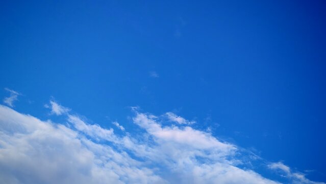 Minimalist composition of bright blue sky with thin white wispy clouds forming clean diagonal pattern suitable for digital backgrounds or marketing creative assets.