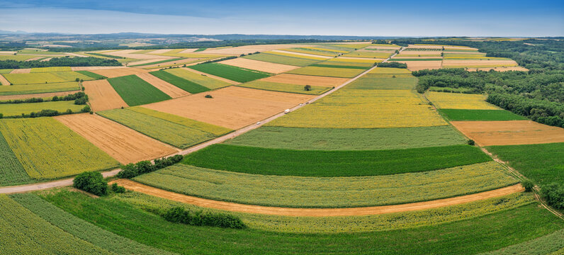 Aerial view showing a vibrant agricultural landscape with colorful patchwork fields, crops, and a rural road