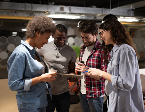 Cheerful diverse colleagues using tablet during break in coworking