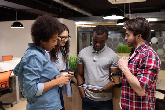 Diverse colleagues watching video on tablet during break in coworking