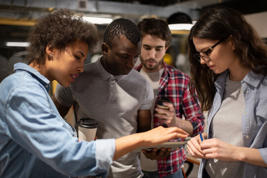 Serious multiethnic team browsing project data on tablet in coworking