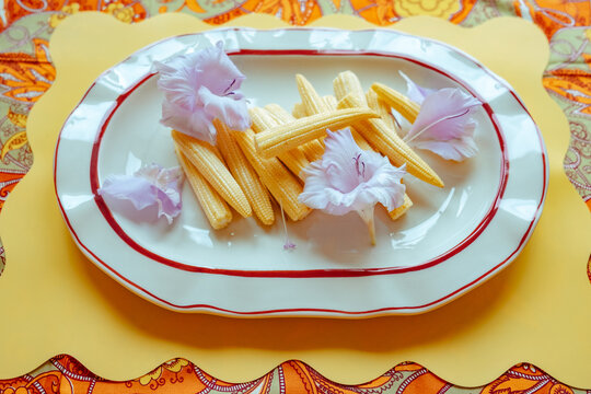 Fresh baby corn and edible flowers on a plate