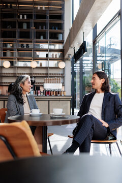 Two people in suits converse over coffee