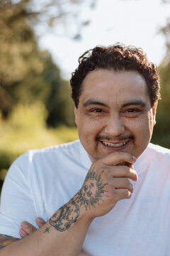 Candid portrait of a smiling man with sun tattoo outdoors
