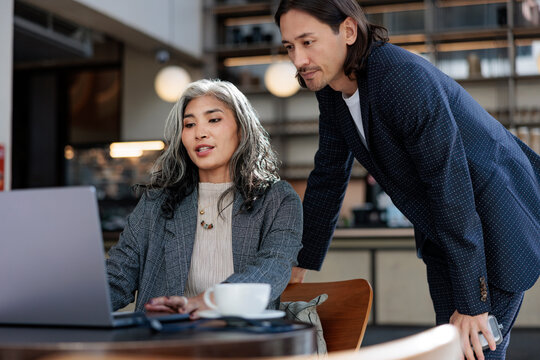 Business colleagues collaborate on a laptop in a cafe
