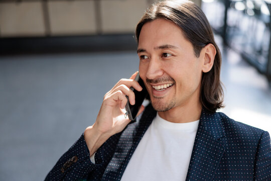 Smiling man in blazer talking on phone.