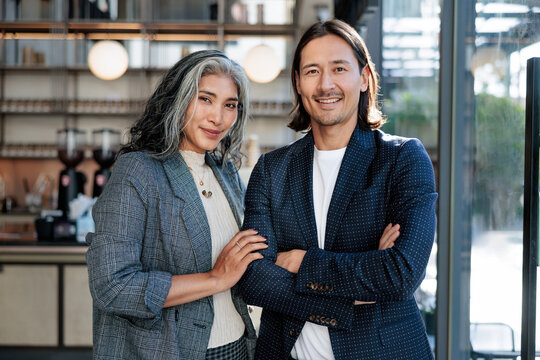 Two smiling business professionals pose in a modern cafe