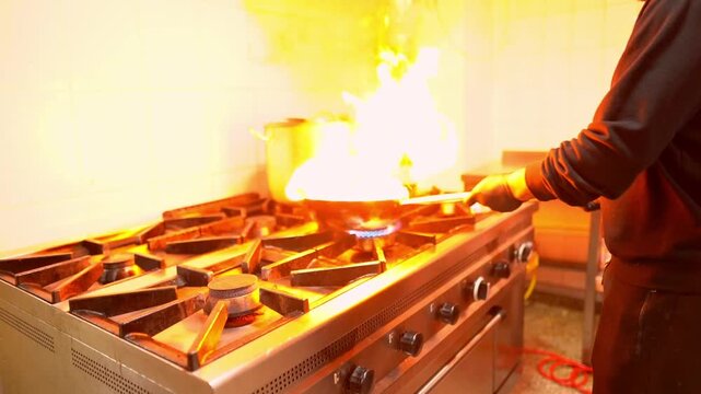 Professional chef flambeing food in a restaurant kitchen