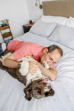 Senior man hugging playful curly dog during relaxed time at home