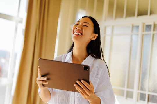 Woman laughing enjoying content on tablet computing device