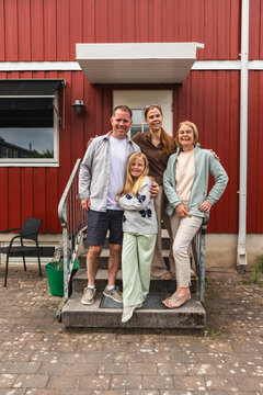 Multigenerational family portrait standing on front steps of house